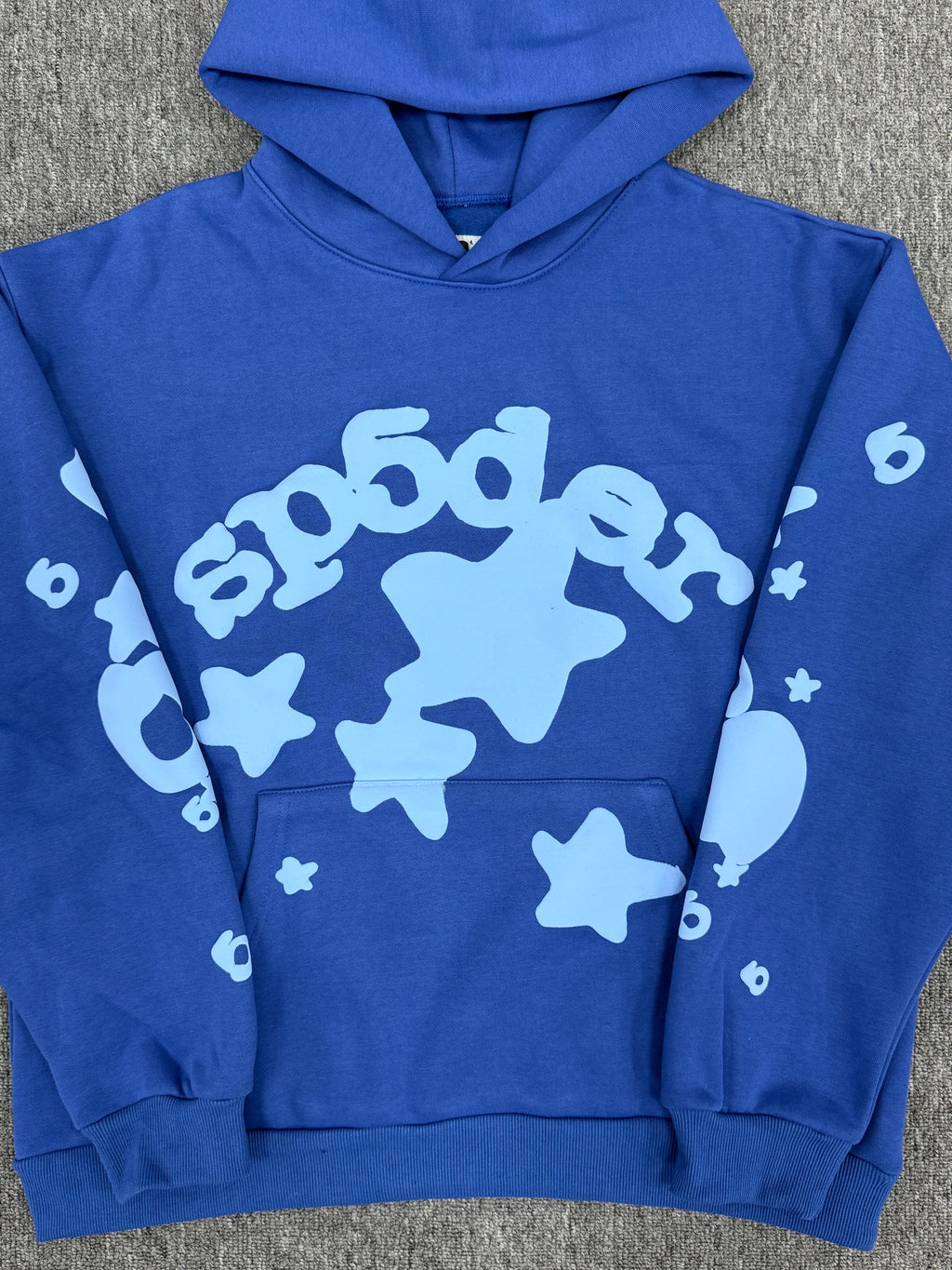 blue Sp5der Beluga hoodie features a distinct light blue graphic print of stars and the brand name on the front and sleeves