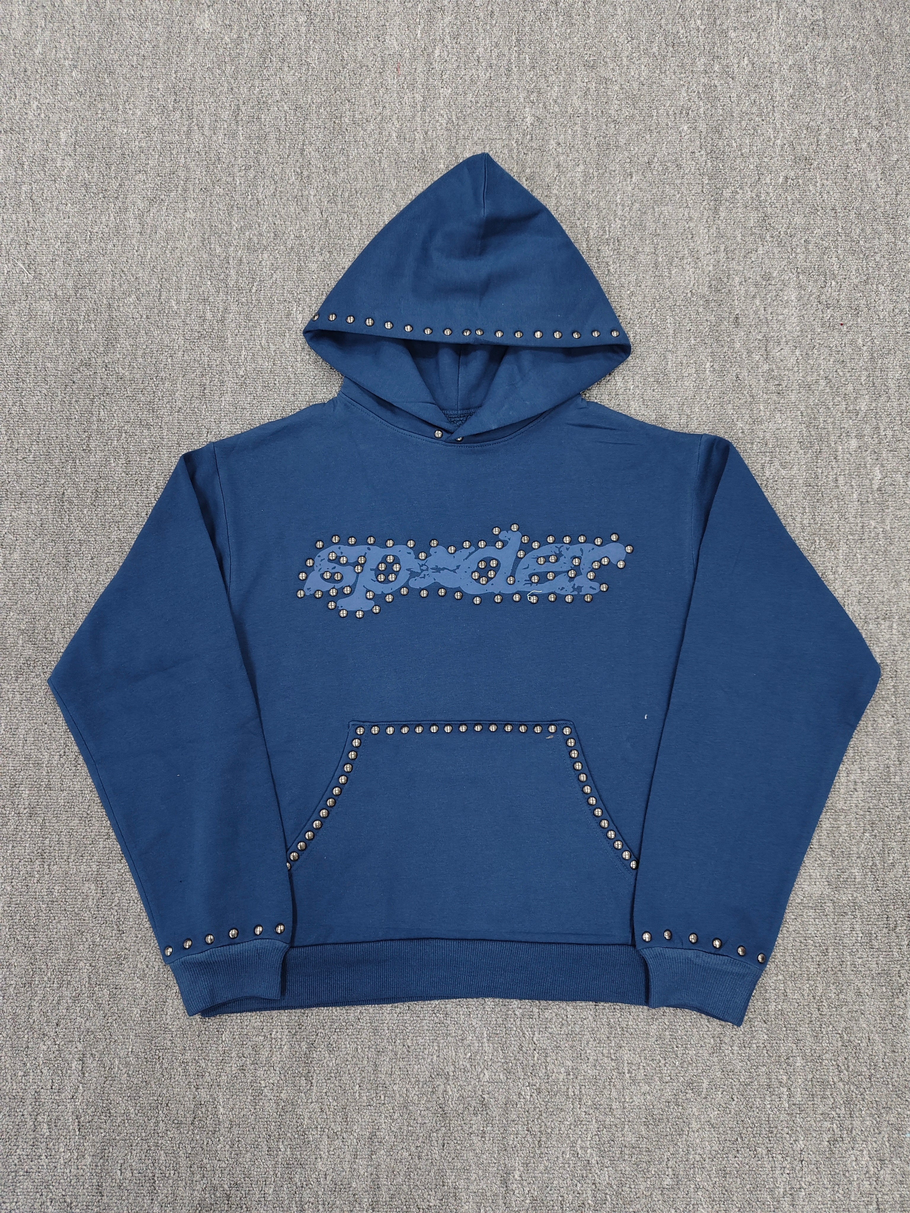 a blue Sp5der Punk V3 Studded Hoodie, featuring rhinestone-accented branding and silver stud details along the hood, logo, and pocket