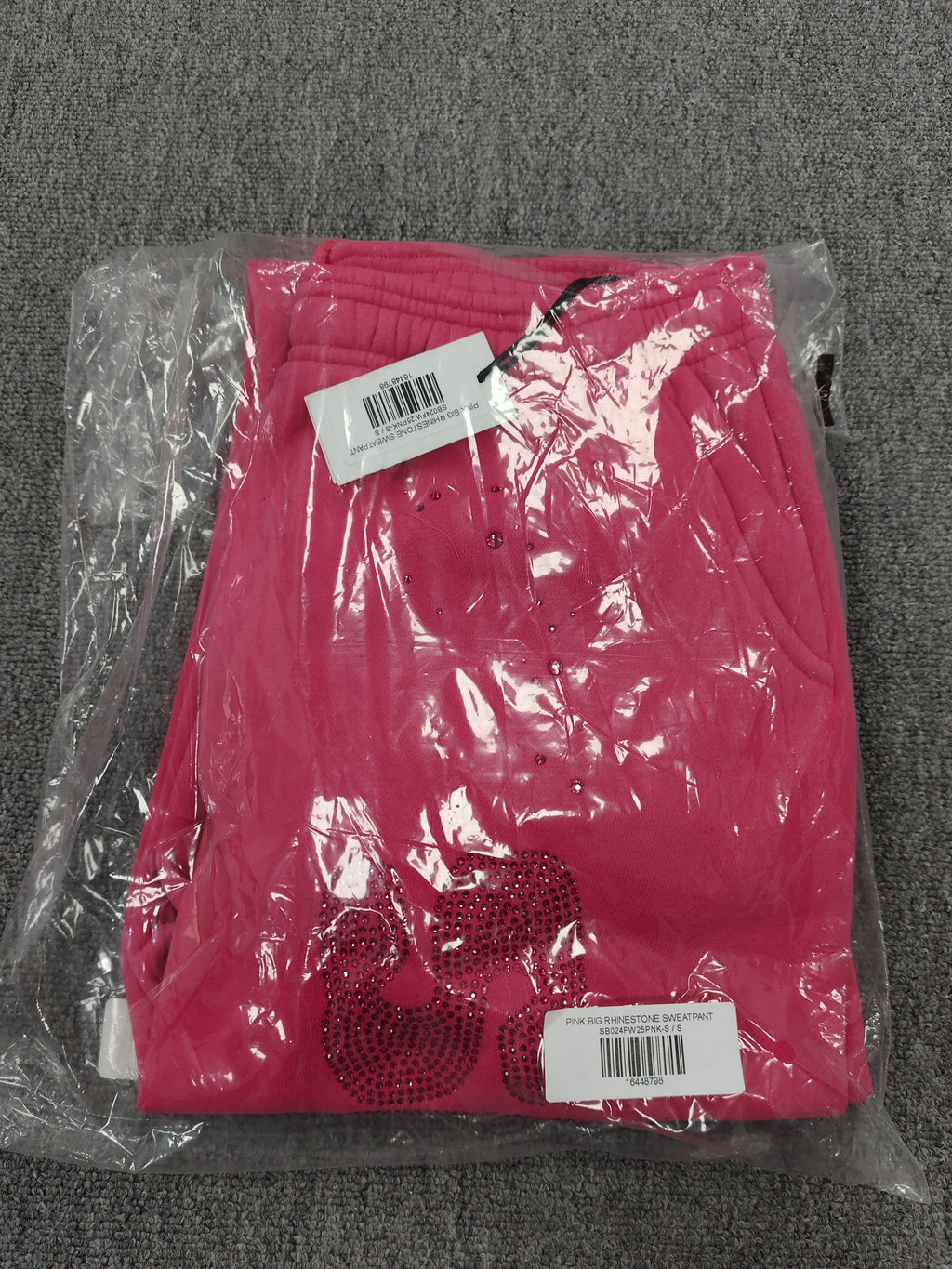 pink Sp5der sweatpants feature rhinestone branding down the leg and are identified as the Rhinestone Silk Sweatpant model