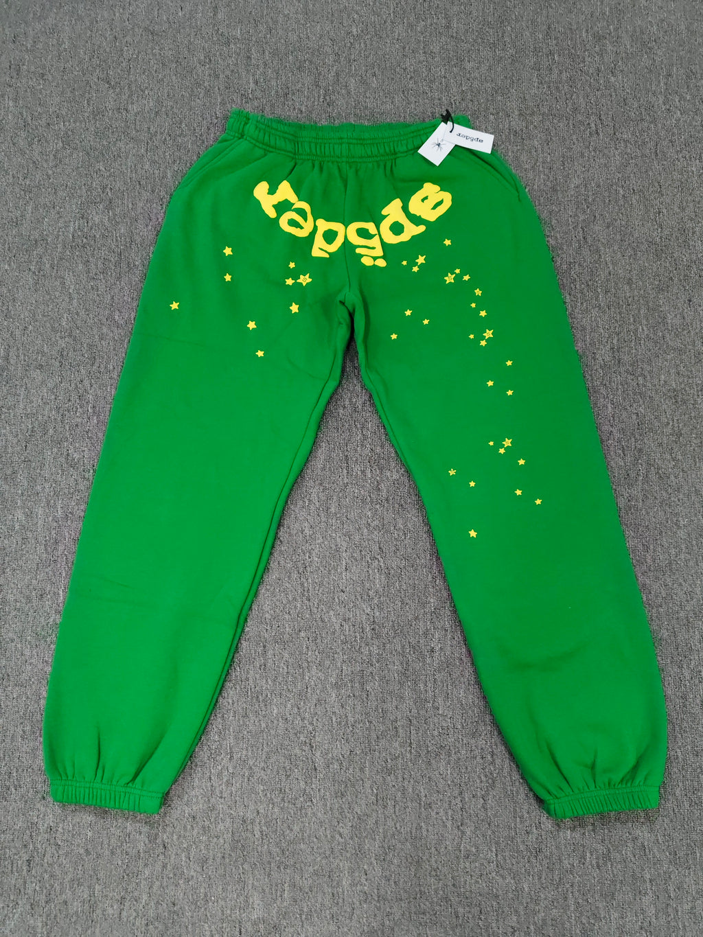 Sp5der Star OG Web V2 Sweatpants in the Slime Green colorway, featuring scattered yellow star motifs and a yellow brand graphic