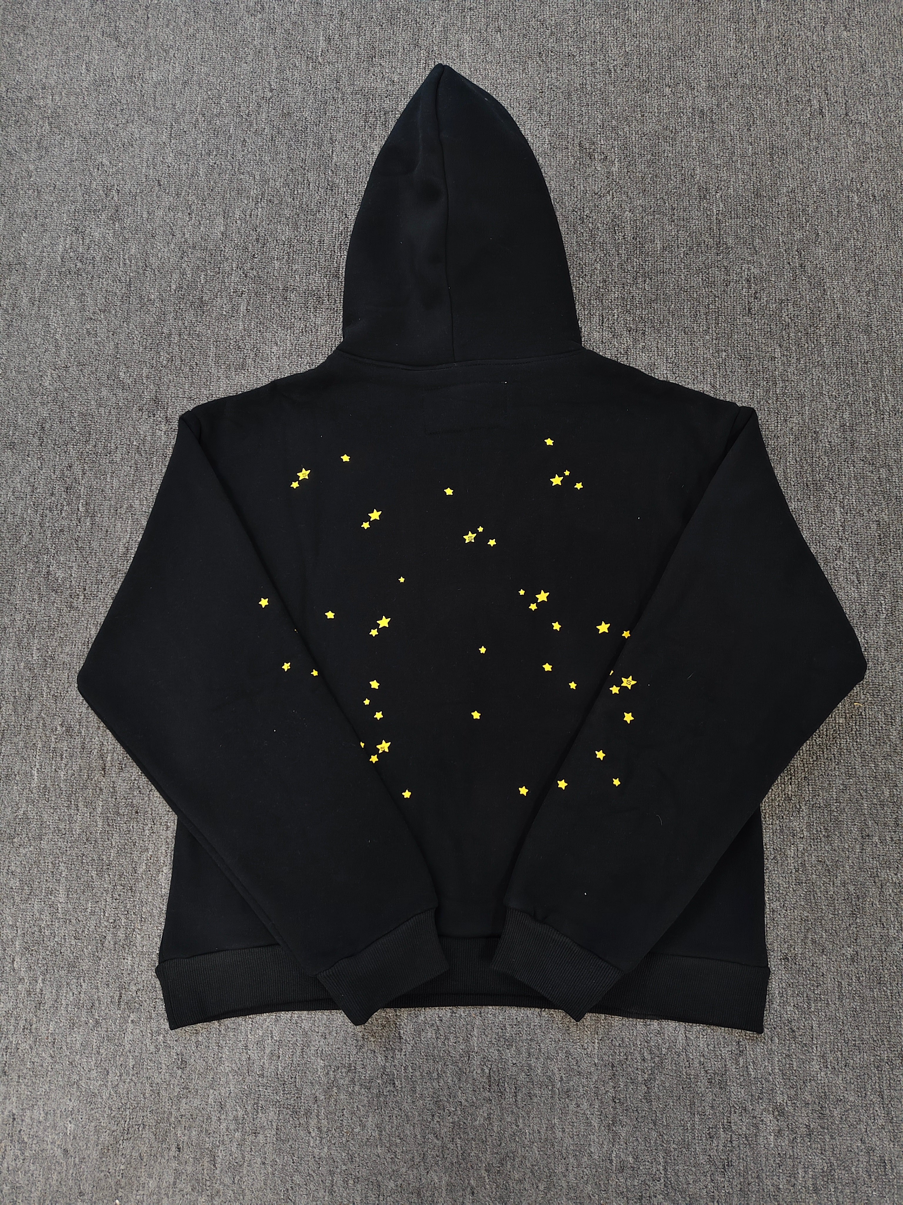 black SP5DER Atlanta hoodie features yellow lettering, red stars, and a spiderweb graphic