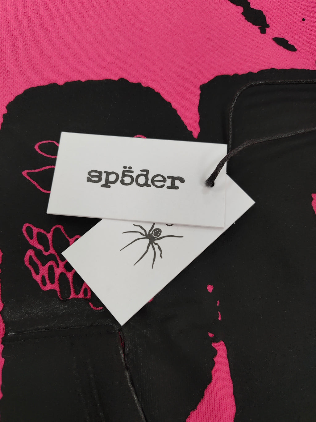 hot pink Sp5der hoodie featuring large, bold black screen-printed graphics on the front and arms.