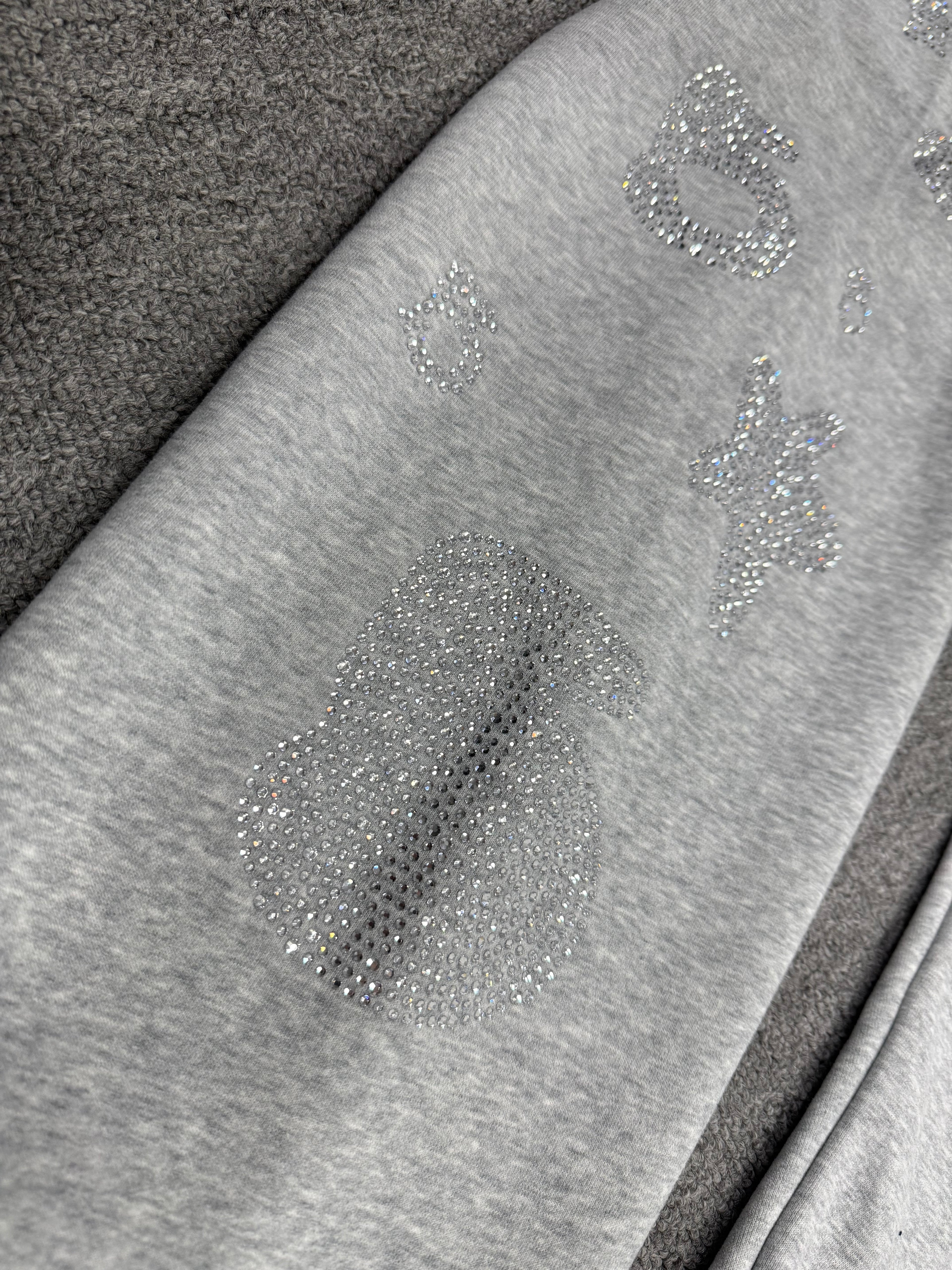 light grey sp5der joggers feature a unique rhinestone across the front hip area