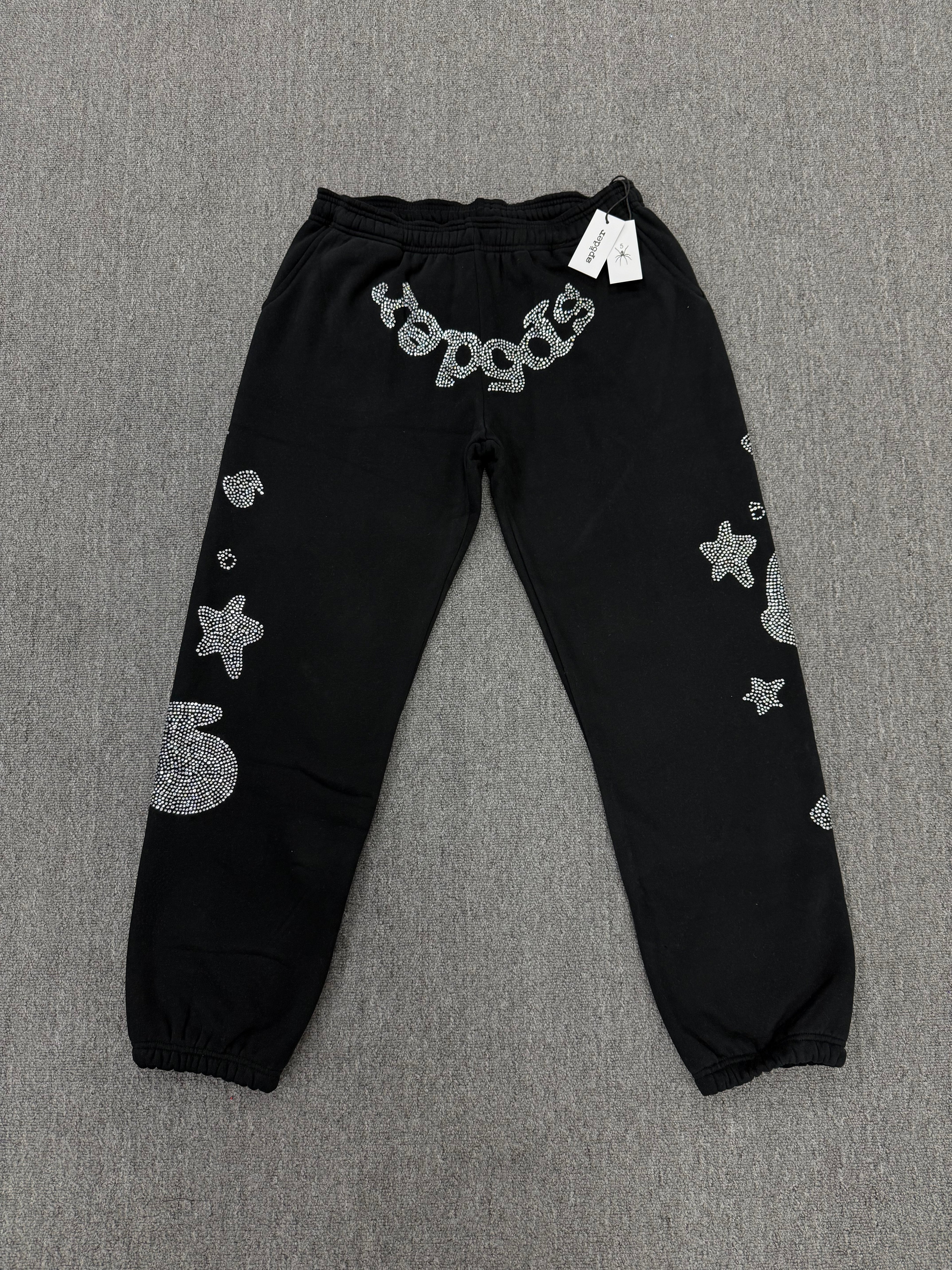 Sp5der OG Web Sweatpants in black, featuring distinctive rhinestone logo and star graphics