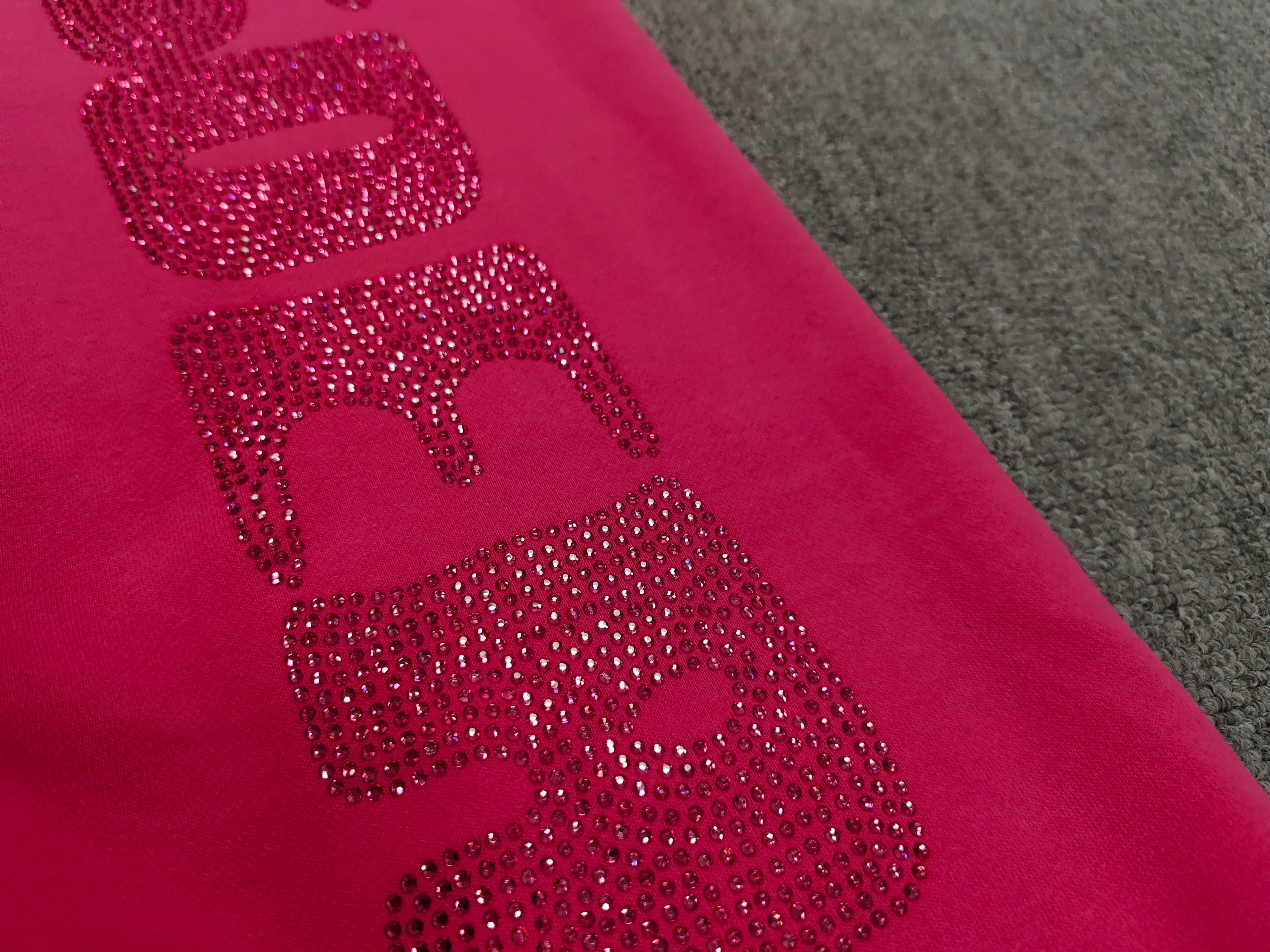 pink Sp5der sweatpants feature rhinestone branding down the leg and are identified as the Rhinestone Silk Sweatpant model
