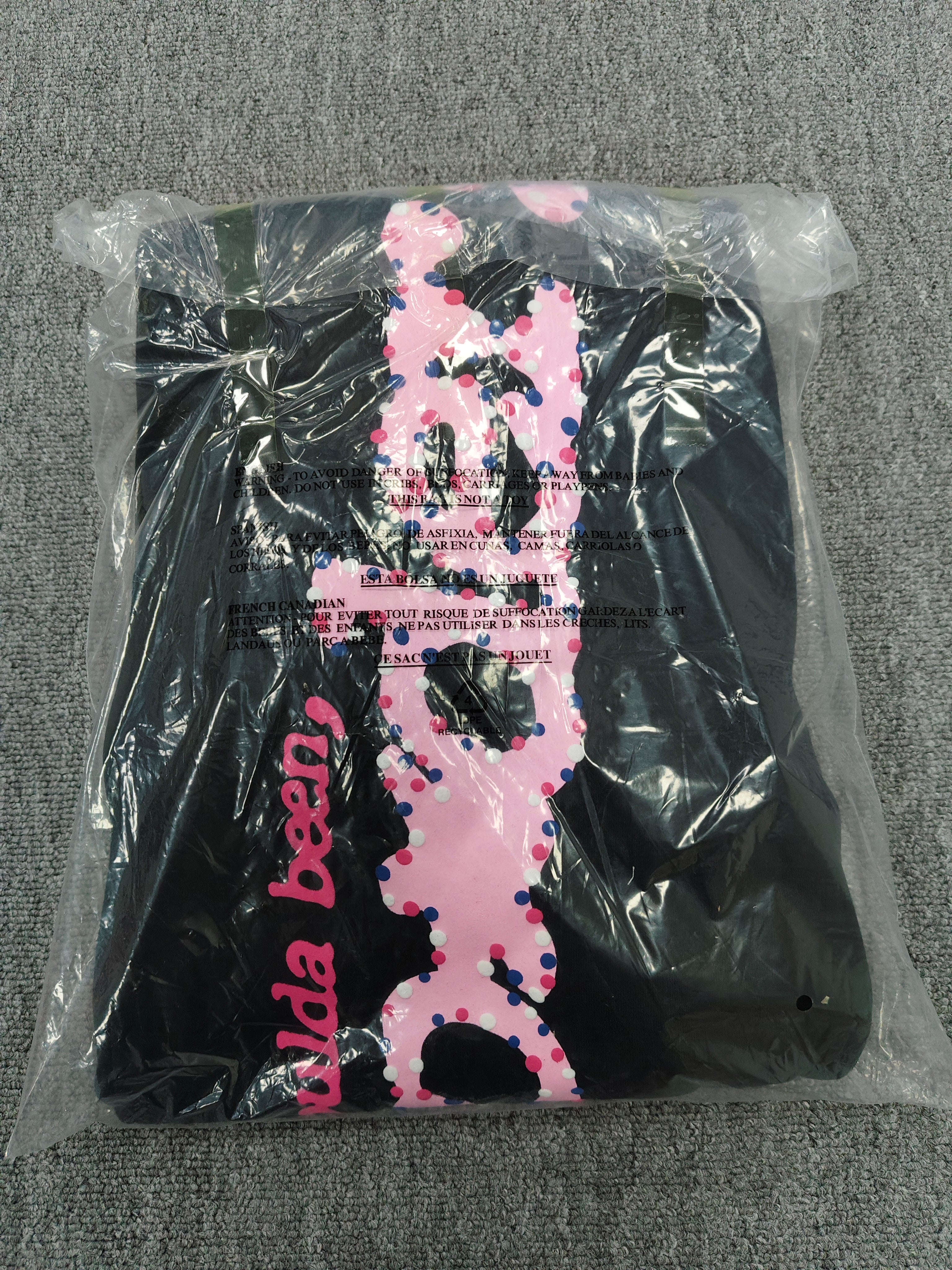 black Sp5der x Coulda Been sweatpants featuring a prominent pink "spider!" graphic and multi-colored star embroidery