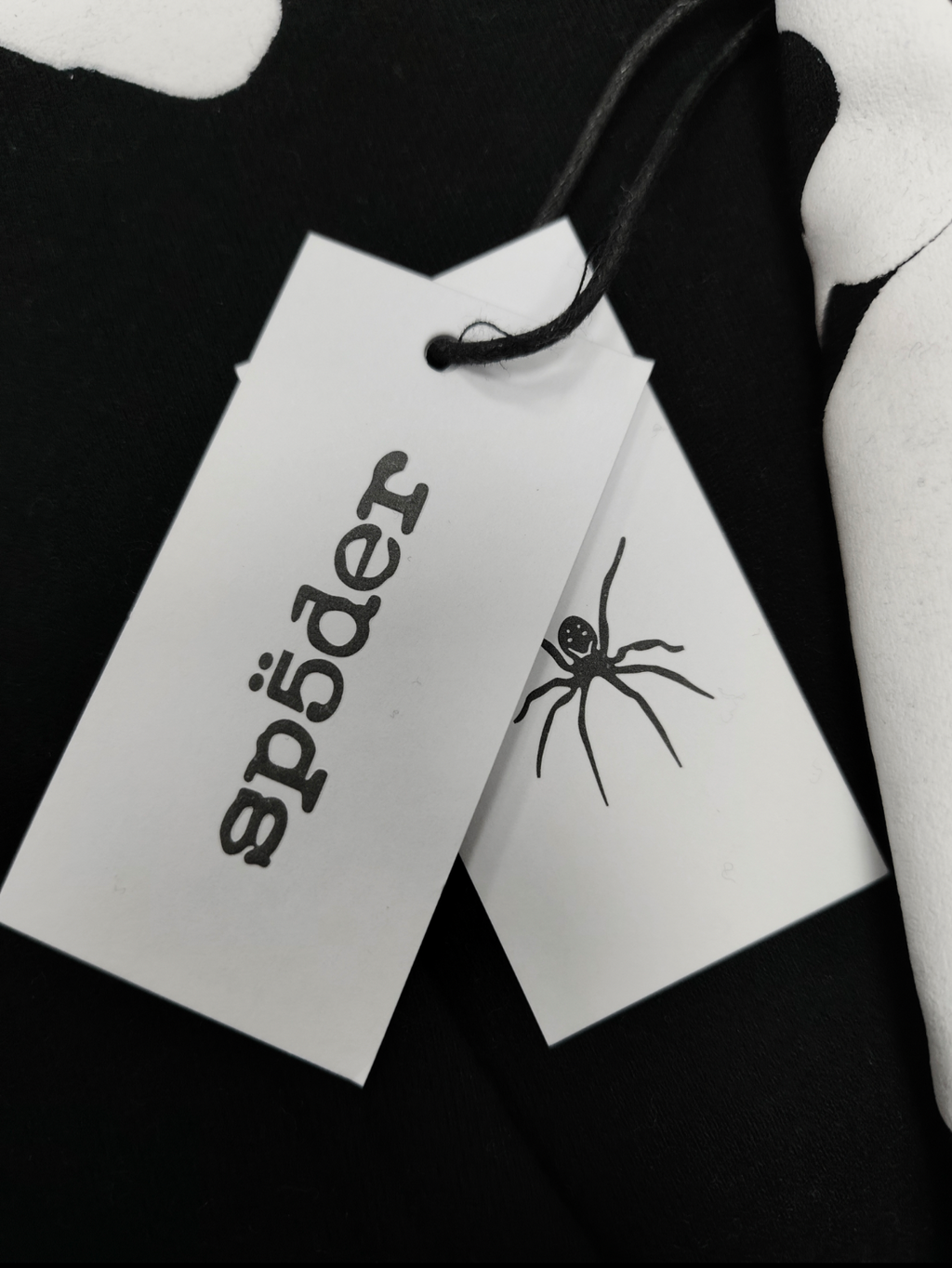black Sp5der hoodie features reflective white graphic prints of the brand name and stars