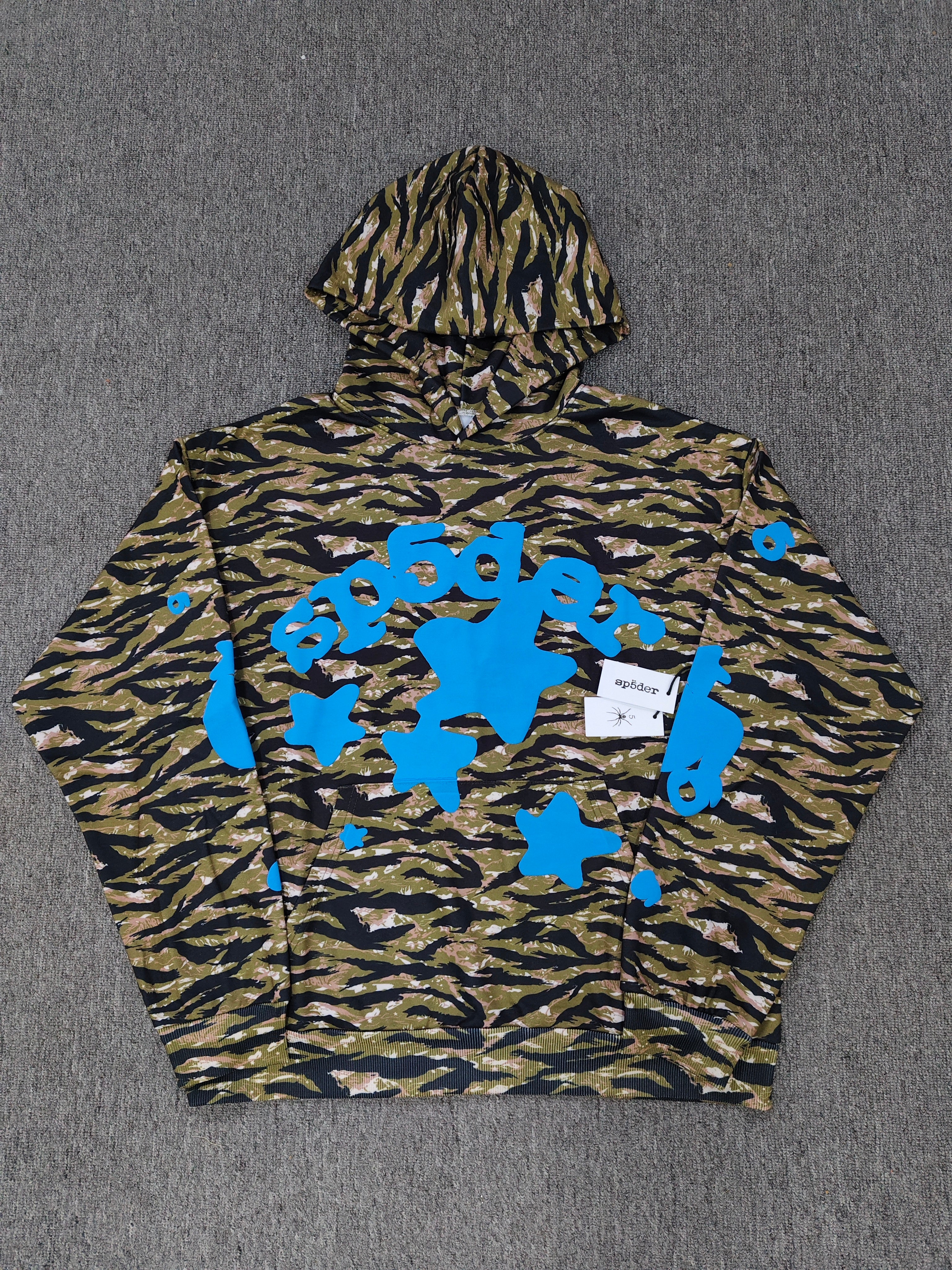 Sp5der Beluga hoodie features a distinct tiger camo pattern and vibrant blue star graphics