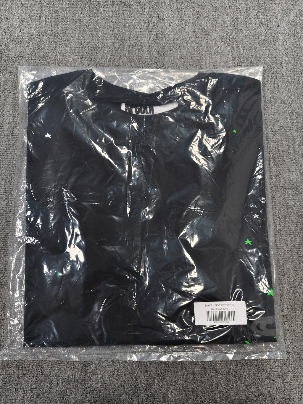 a Sp5der Heavy Web T-shirt in black featuring a prominent neon green web graphic and scattered star print