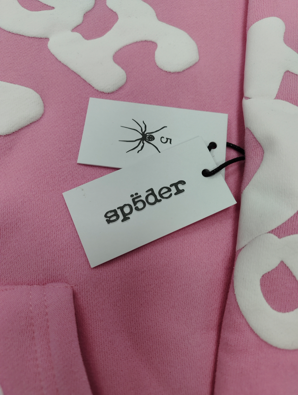 Sp5der pink graphic pullover hoodie features a prominent white screen-printed spiderweb design on the front