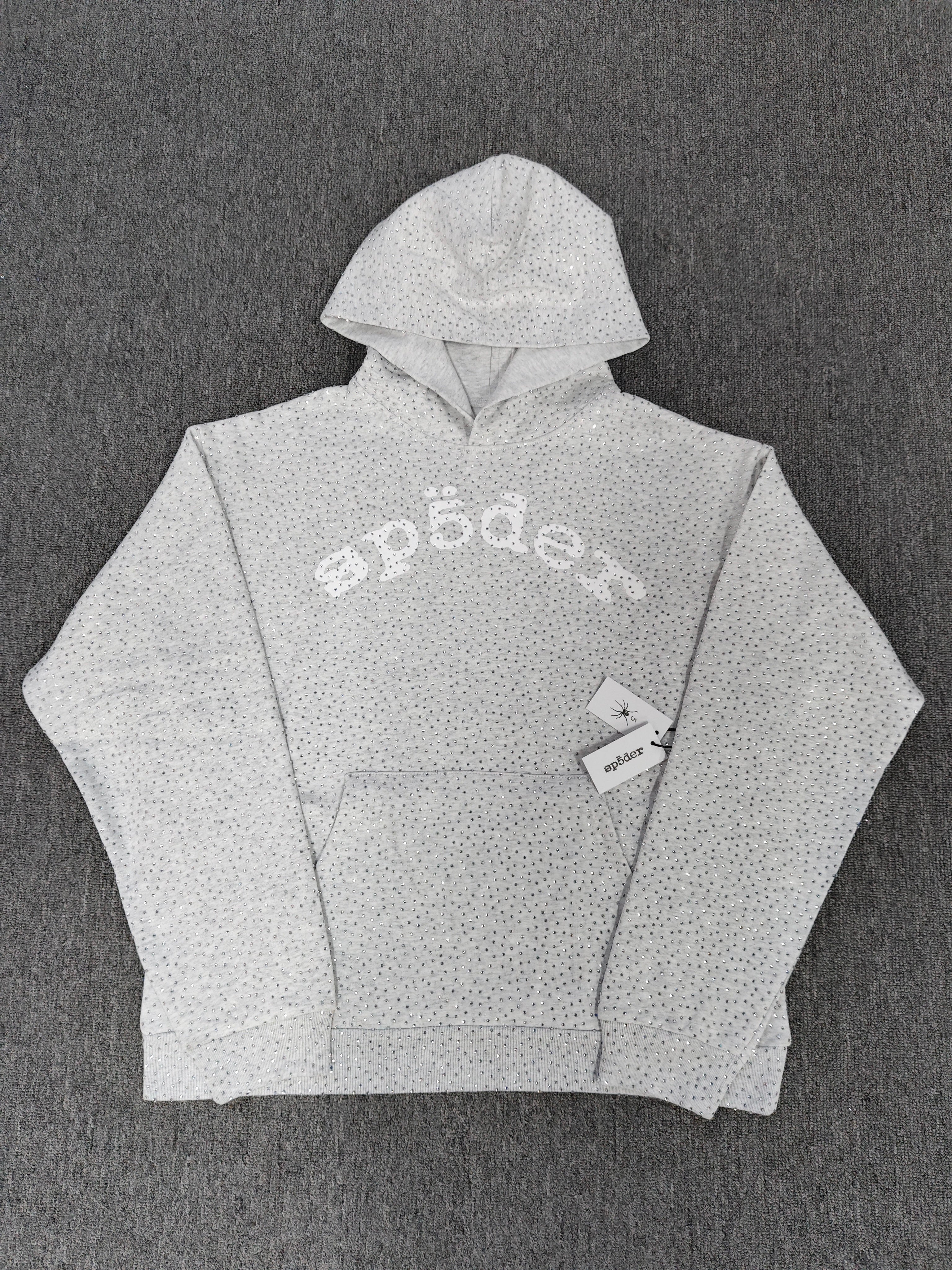 a Sp5der VVS Hoodie in Heather Grey, recognized by its all-over tonal rhinestones and arch logo