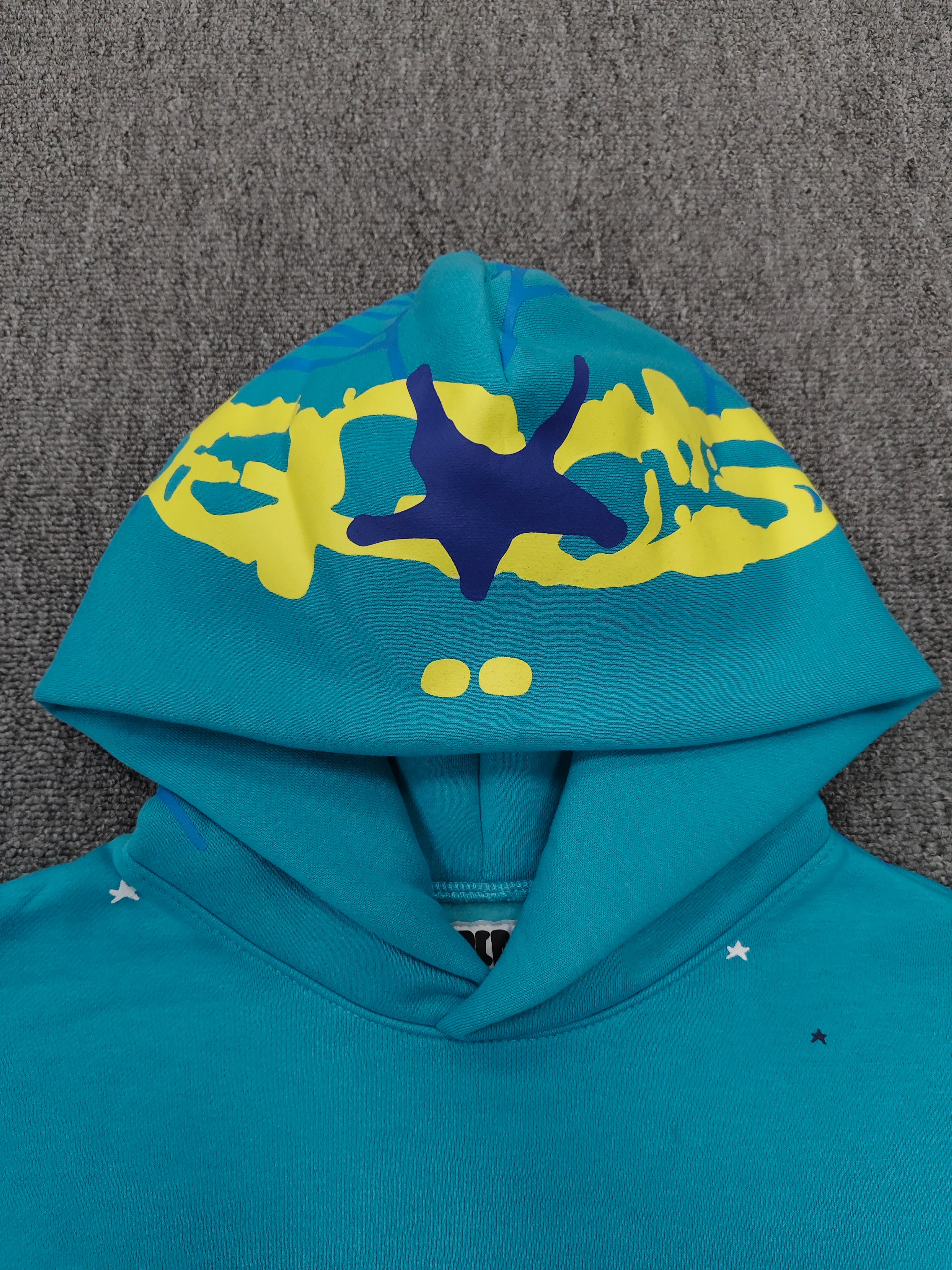 Sp5der Heavy Web Hoodie in 'Cyan' is designed with a striking blue color and a signature web-inspired graphic on the hood