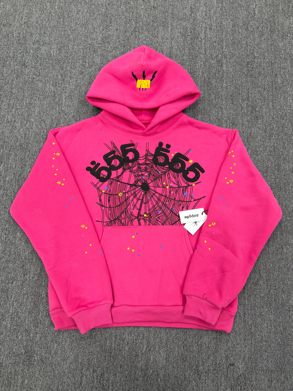 pink Sp5der graphic-print hoodie features a black spiderweb design on the front with scattered multicolored stars