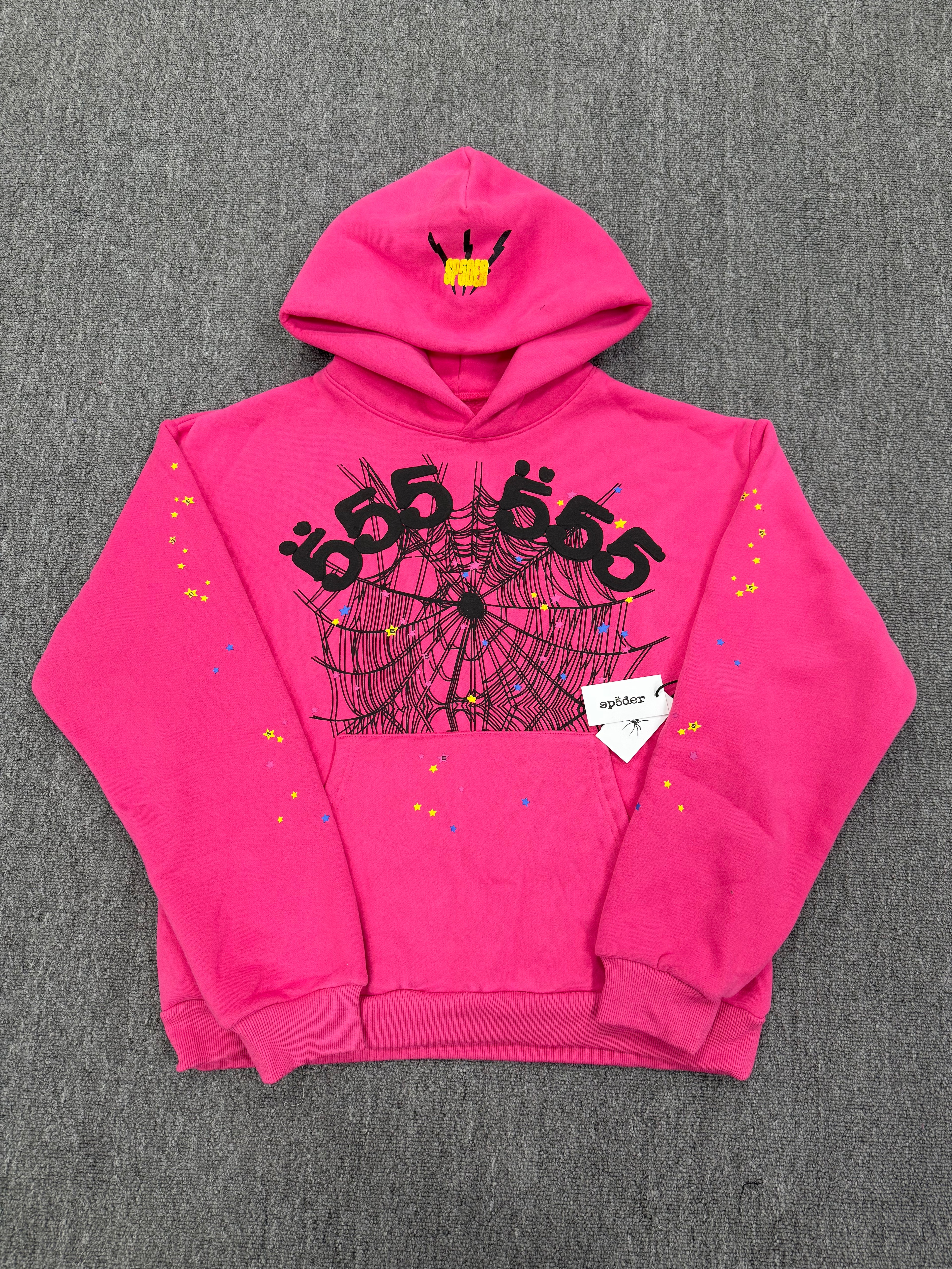 pink Sp5der graphic-print hoodie features a black spiderweb design on the front with scattered multicolored stars