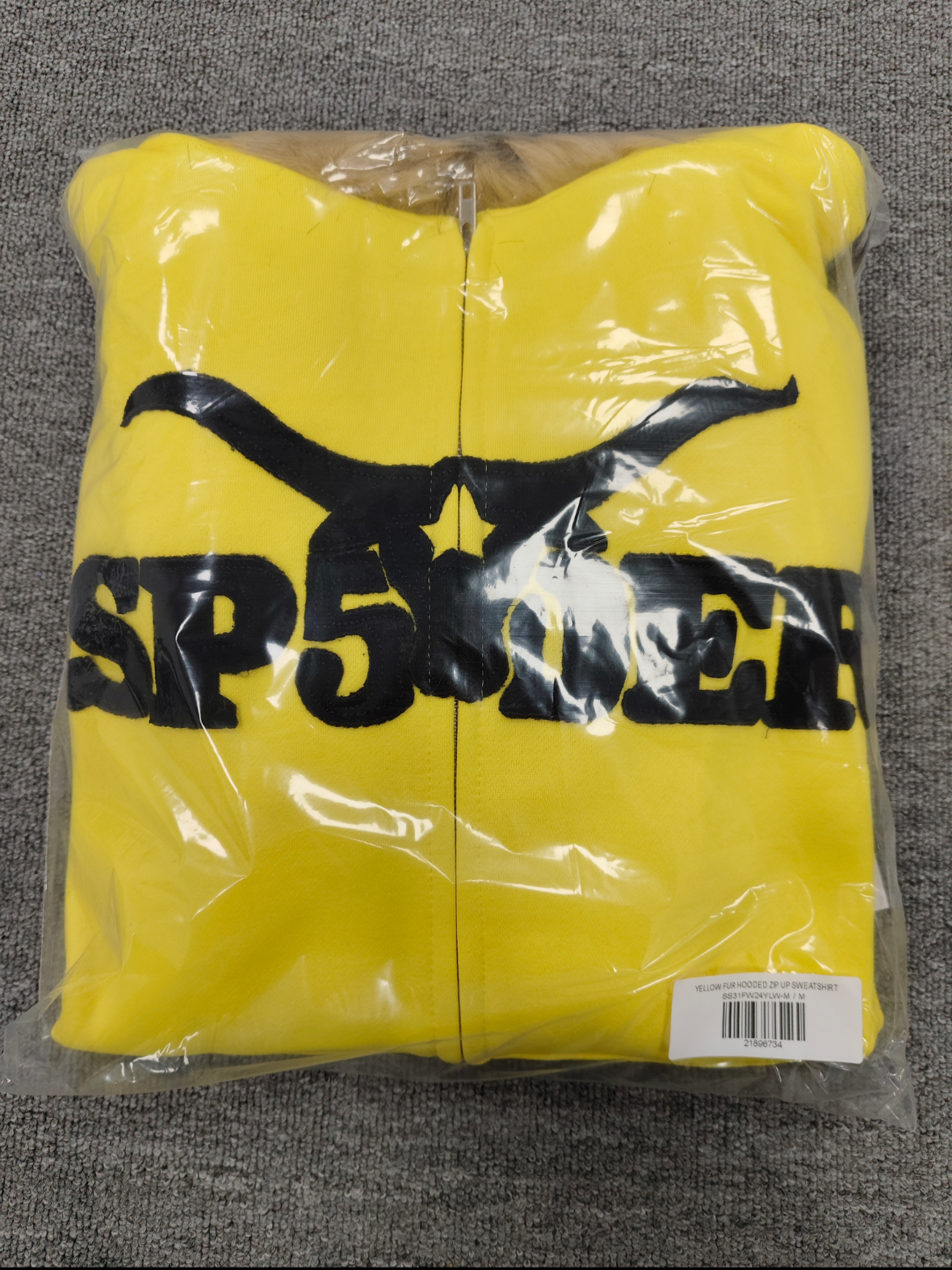 a yellow Sp5der fur-hooded zip-up sweatshirt featuring a prominent black logo and studded sleeve details