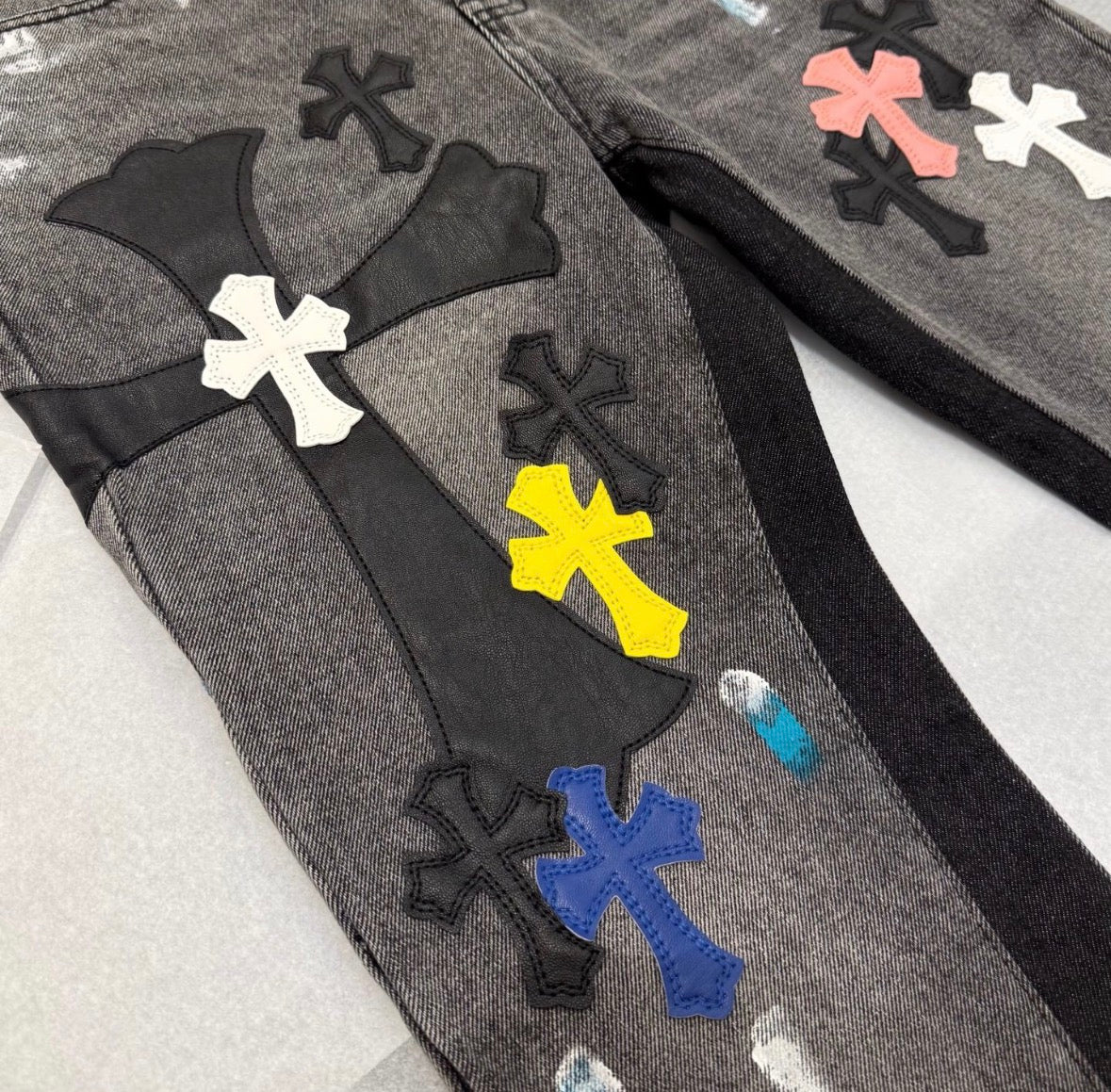 Chrome Hearts distressed jeans featuring a multicolor patchwork application of their iconic cross motif.